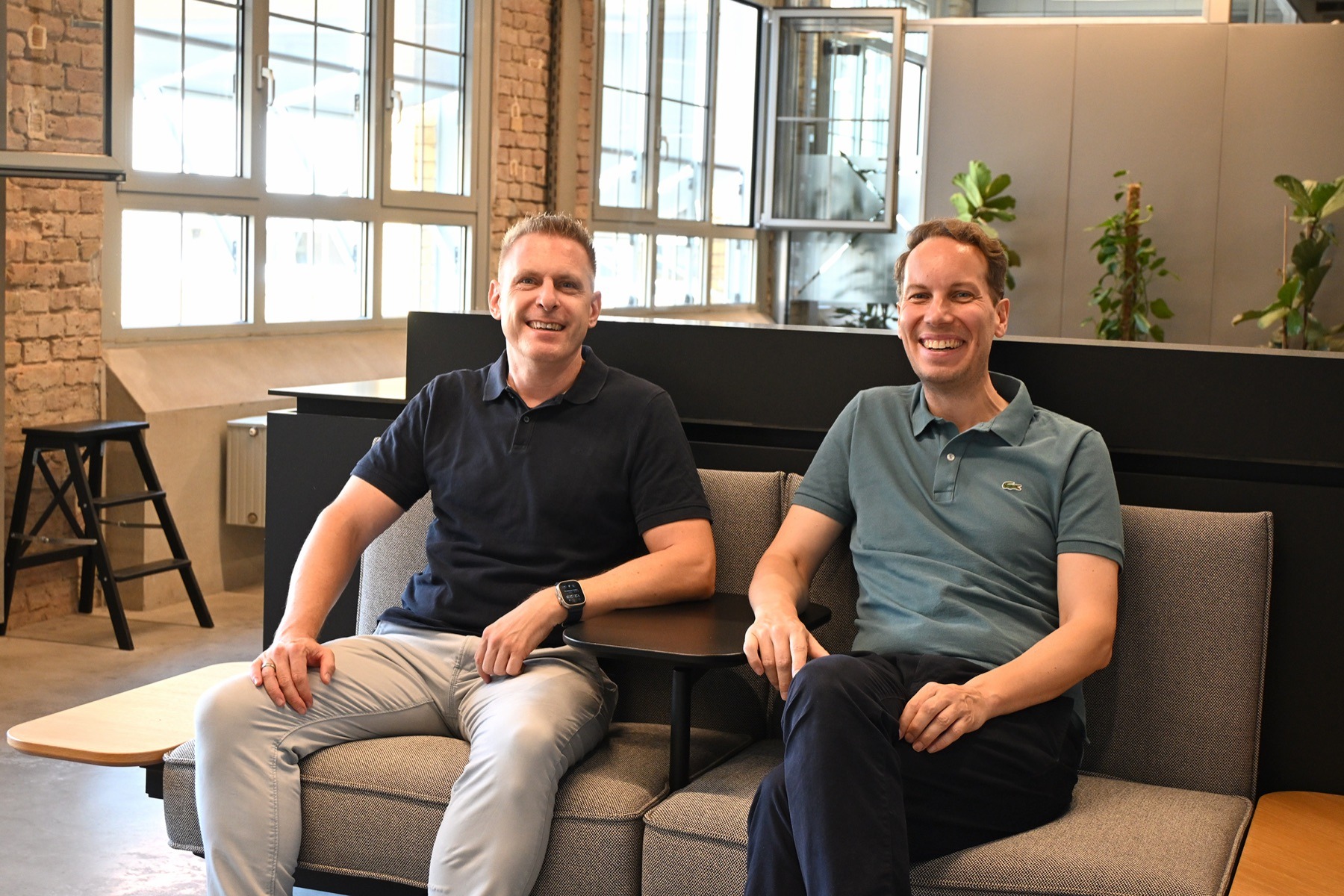 Bernd Mrohs und Markus Grube sitzen entspannt auf einem Sofa im Büro